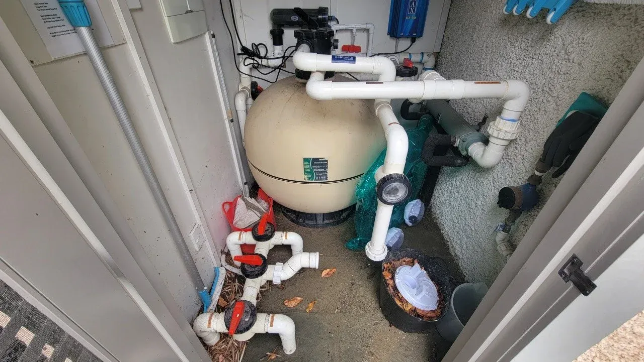 A sand filter, pump and pipework installed in a pool equipment shed.