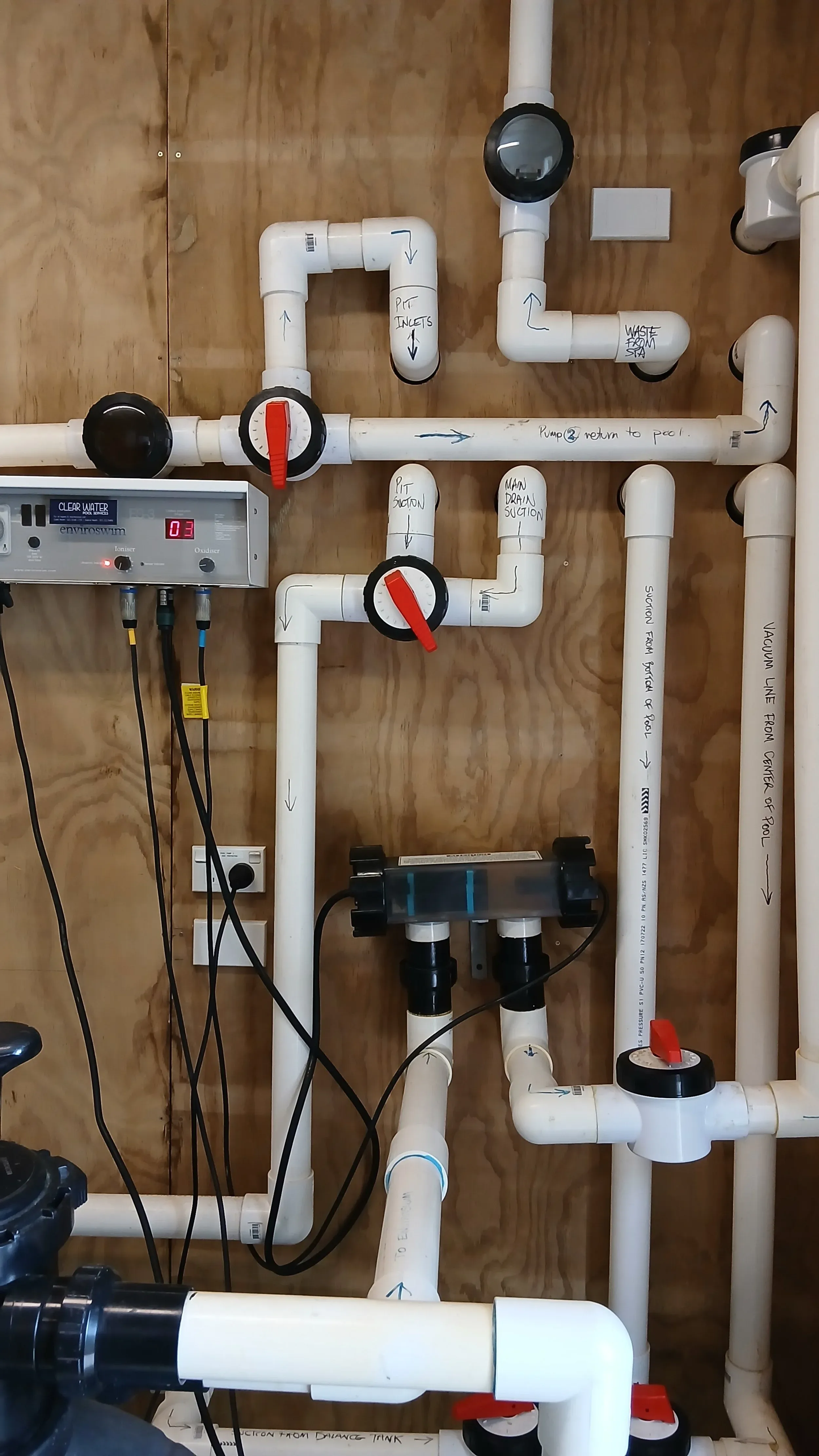 A pool plant room with a chlorinator control box, valves and pipework.