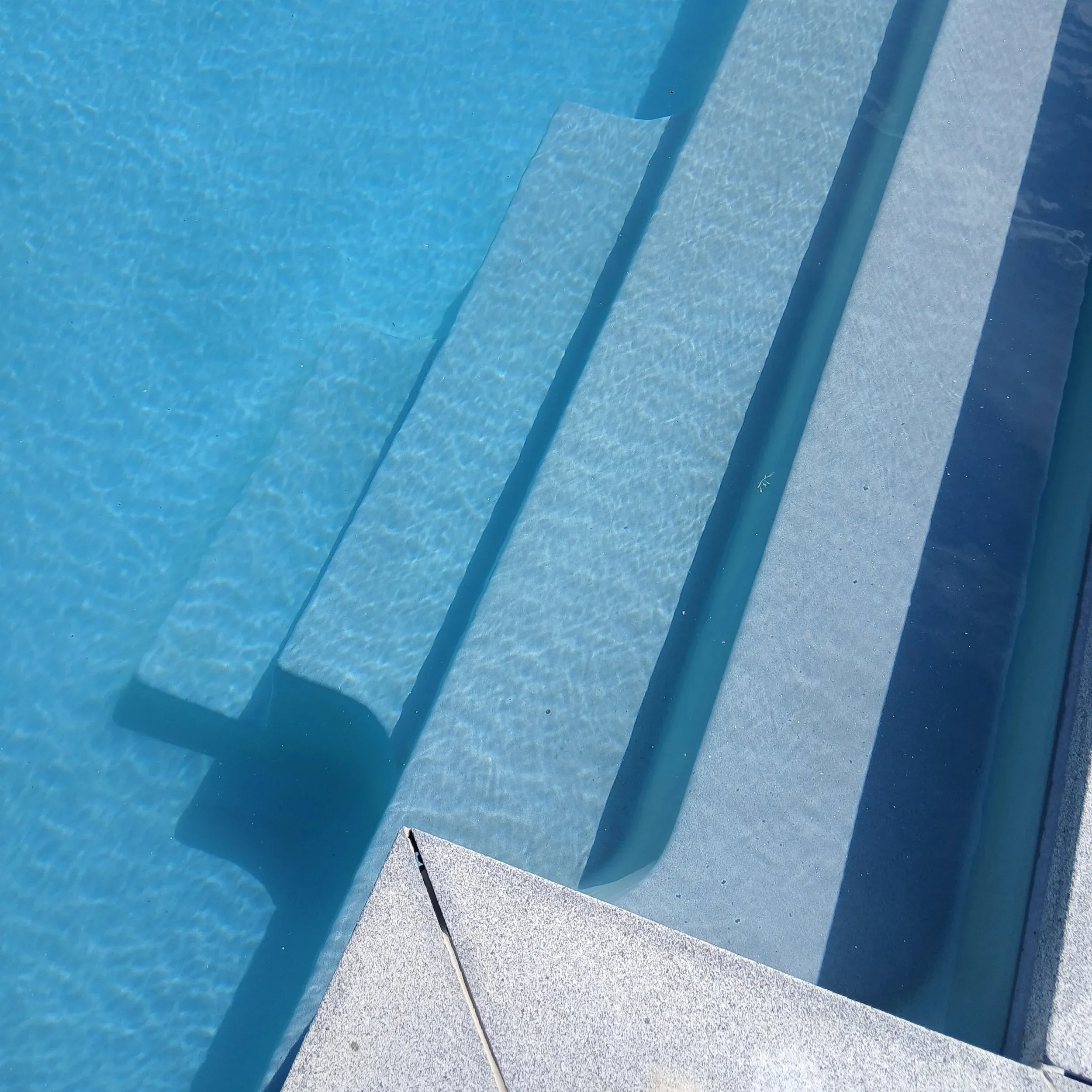 Clear water over pale pool steps.